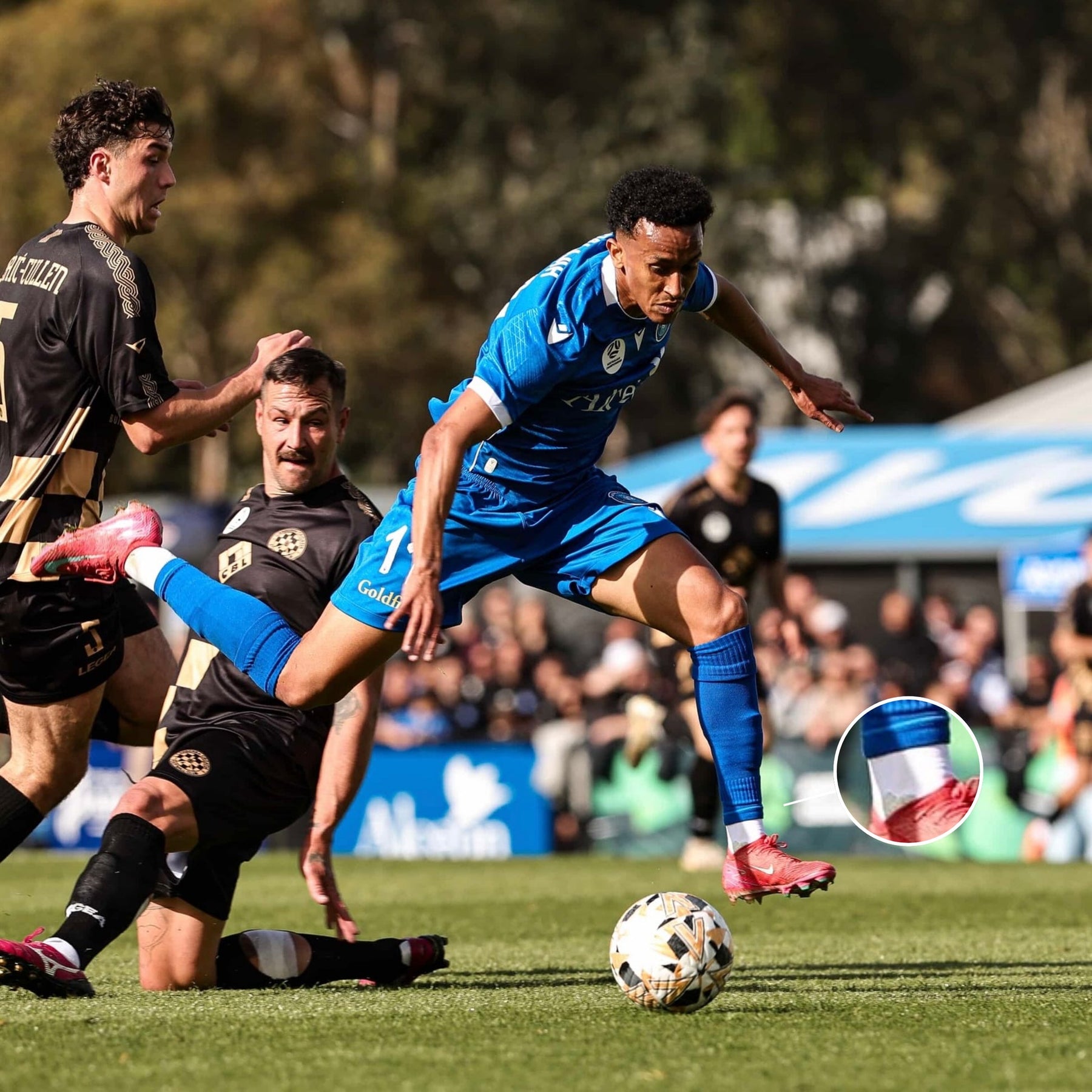 Footballer carrying the ball through a challenge during a match