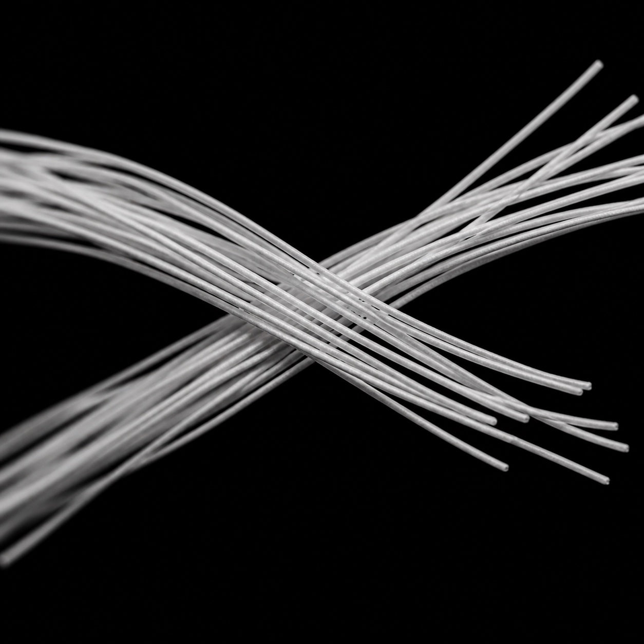 Microscope-style image of fine Nano Grip Yarn filaments crossing in two controlled bundles